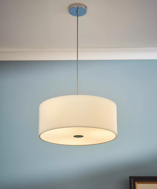 A cream diffuser light hung from the ceiling of a bedroom