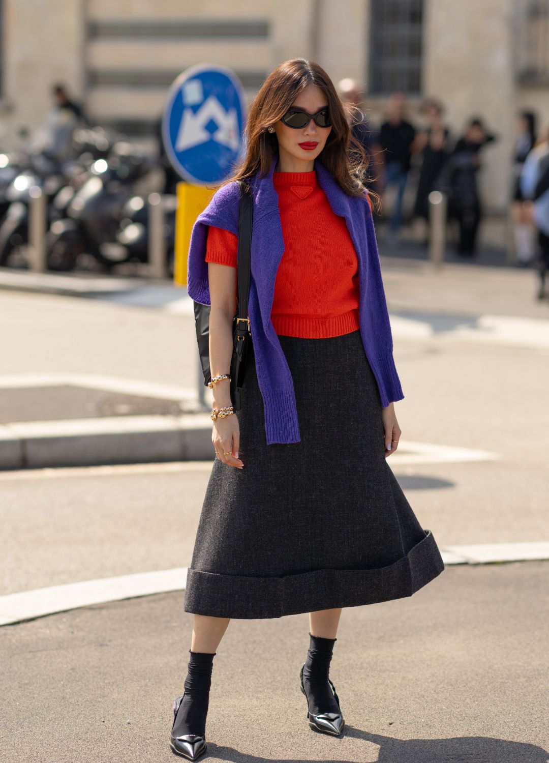 eart Evangelista wearing an orange sweater, a purple sweater, a grey long skirt, glasses is seen outside the Prada show during the Milan Fashion Week Menswear Spring/Summer 2025 on September 19, 2024 in Milan, Italy