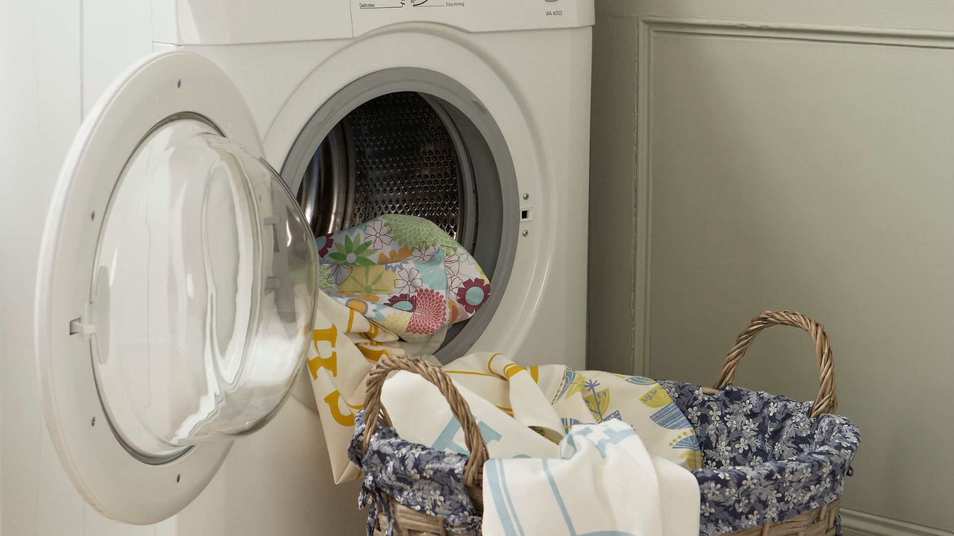 White washing machine with various clothes being put in it
