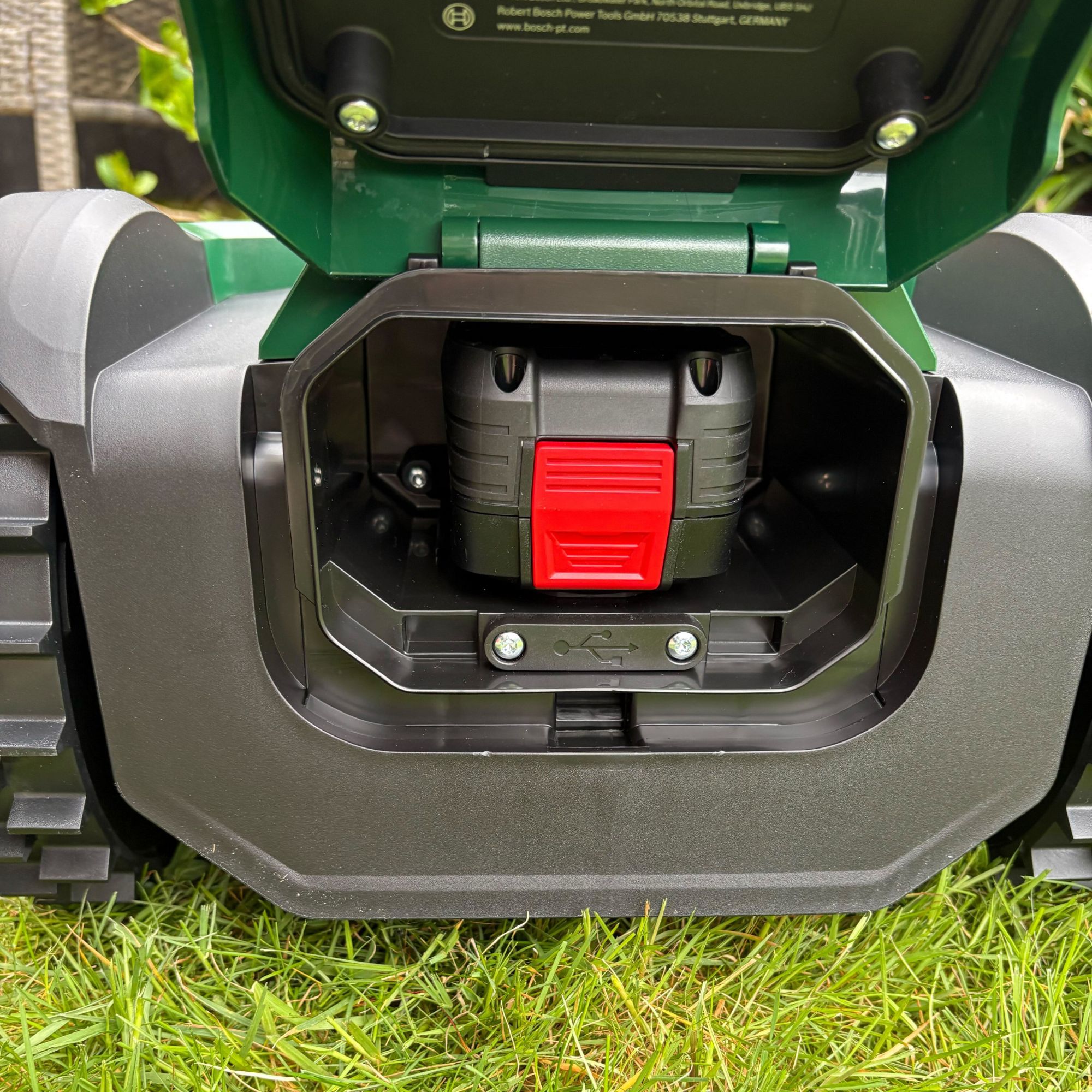 Back view of battery in battery compartment in Bosch VISIMOW18V-100 on grass lawn