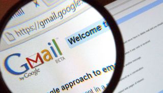 The Gmail logo on a computer screen under a magnifying glass.