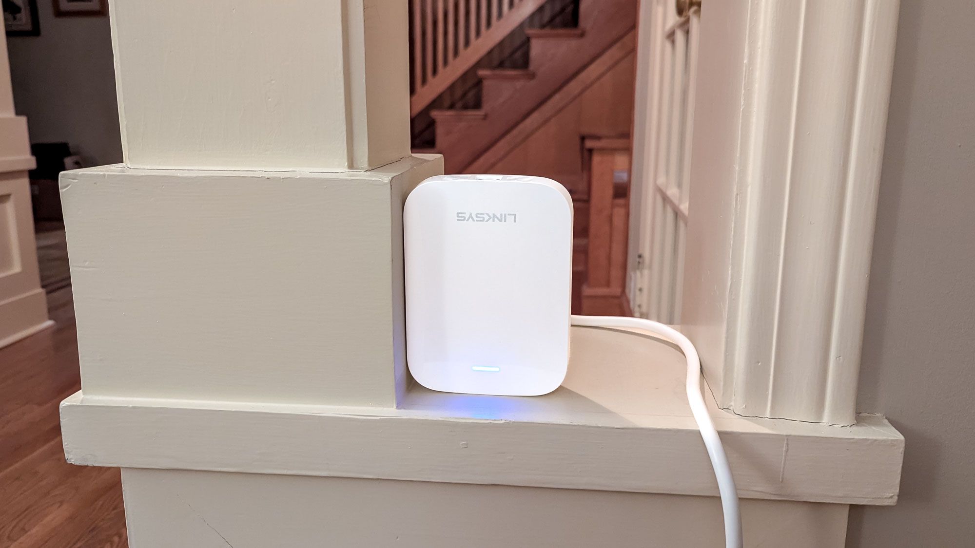 A Linksys RE7350 wi-fi extender in the nook of a shelf.