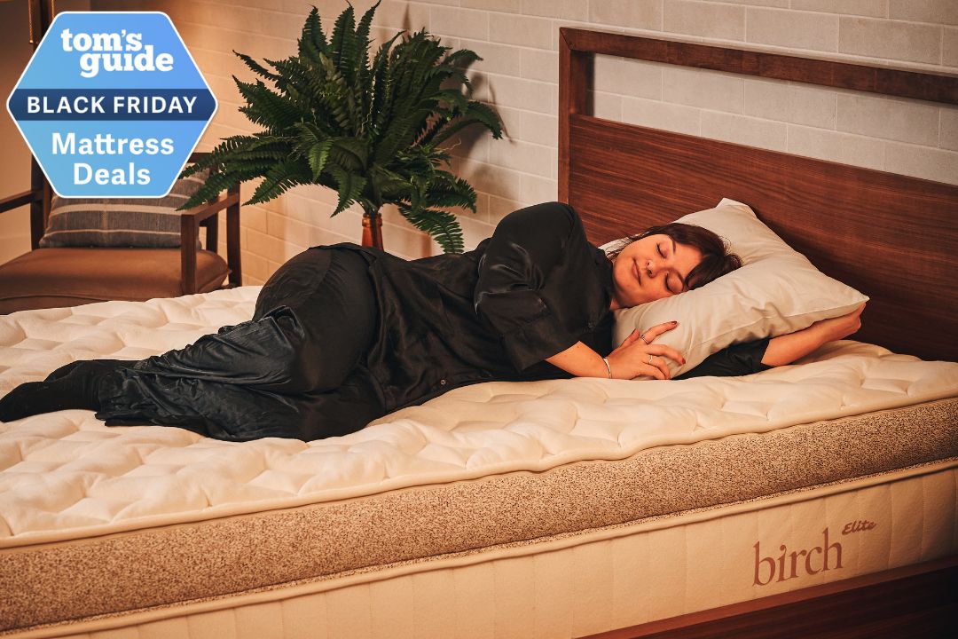 Tom&#039;s Guide Sleep Features Editor lying on the Birch Elite mattress that&#039;s discounted in the Black Friday sales, in a cozy bedroom on a dark wooden bed frame
