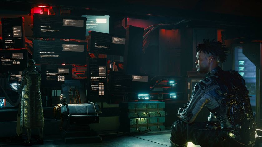 A character in Cyberpunk 2077 sat on a bench while another person interacts with a terminal in front of lots of screens.