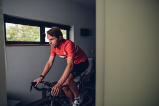 Male cyclist riding indoors on a turbo trainer at a low cadence