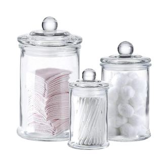 Three glass apothecary jars with cotton pads, balls, and buds in them