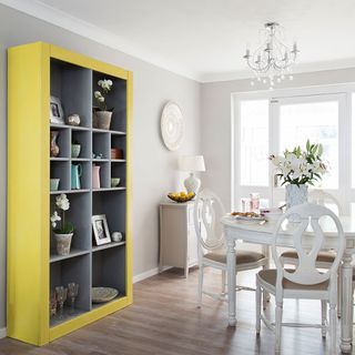 dining area with grey wall wooden flooring grey and yellow shelves dinning table and chair