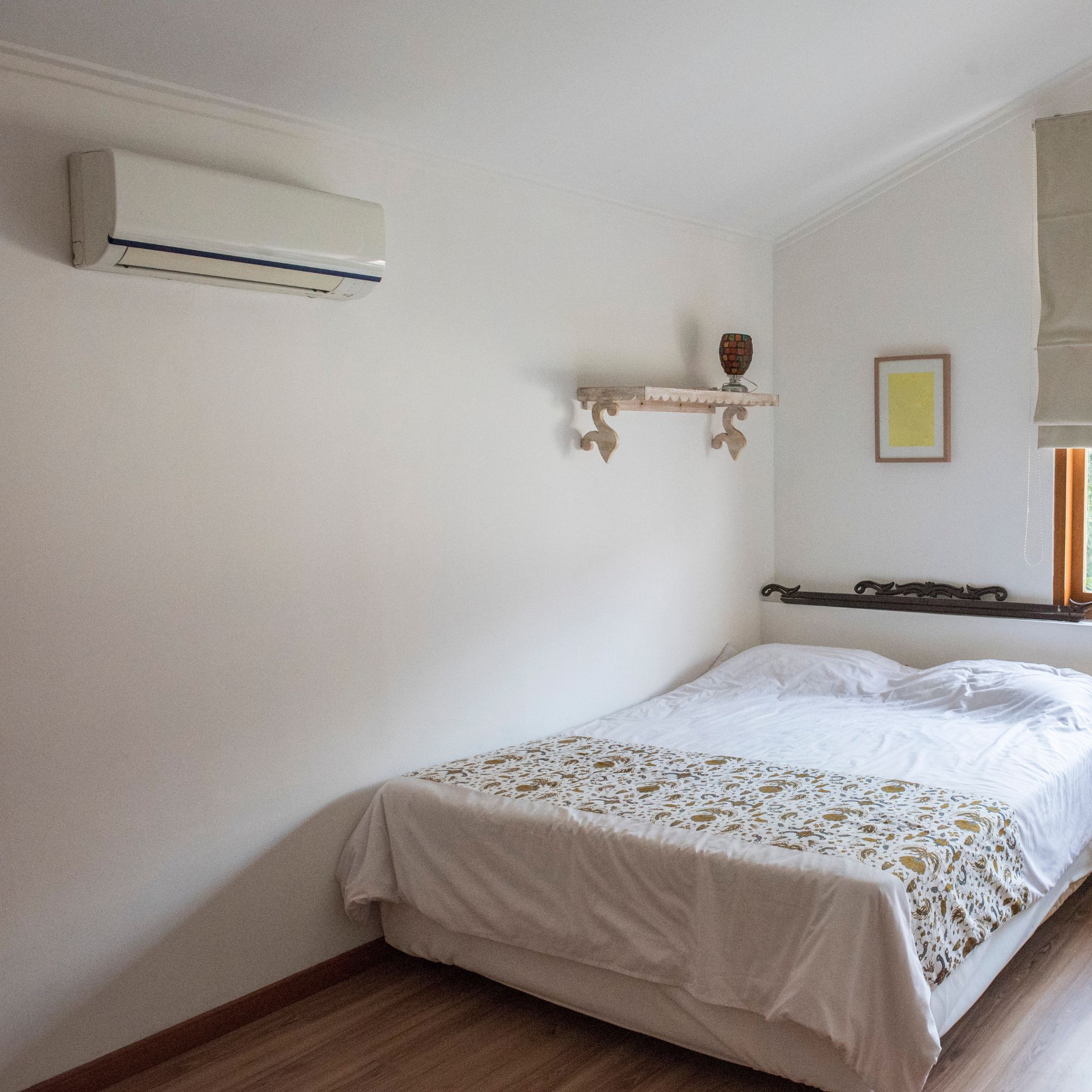 Fitted air con unit on wall of simple guest bedroom