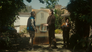 three men stand outside, talking