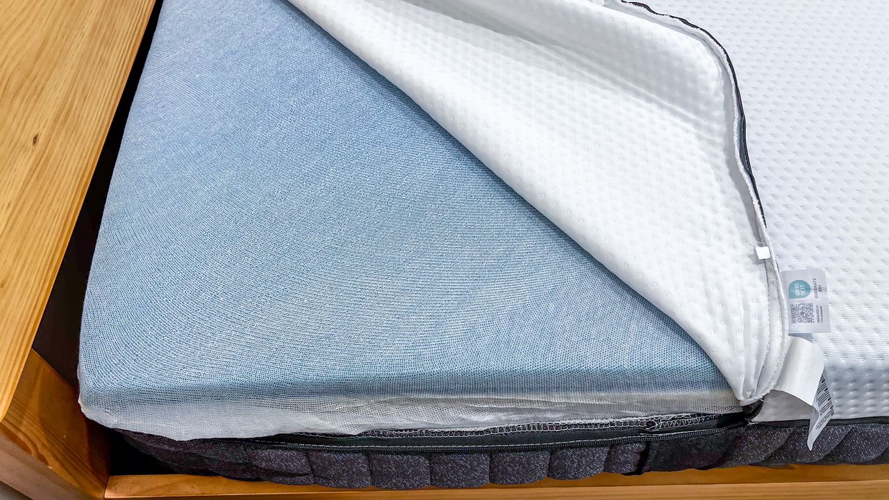 The cover of the Emma Luxe mattress partially open to reveal the cheesecloth wrapping the foams