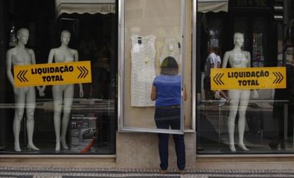 A woman arranges a display outside a Lisbon store: On Tuesday, Moody's slashed recession-plagued Portugal's government bonds to "junk" status.
