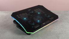 The TopMate C12 Laptop Cooling Pad showing RGB lighting and blue lit fans in front of a pink background at a 3/4s angle.