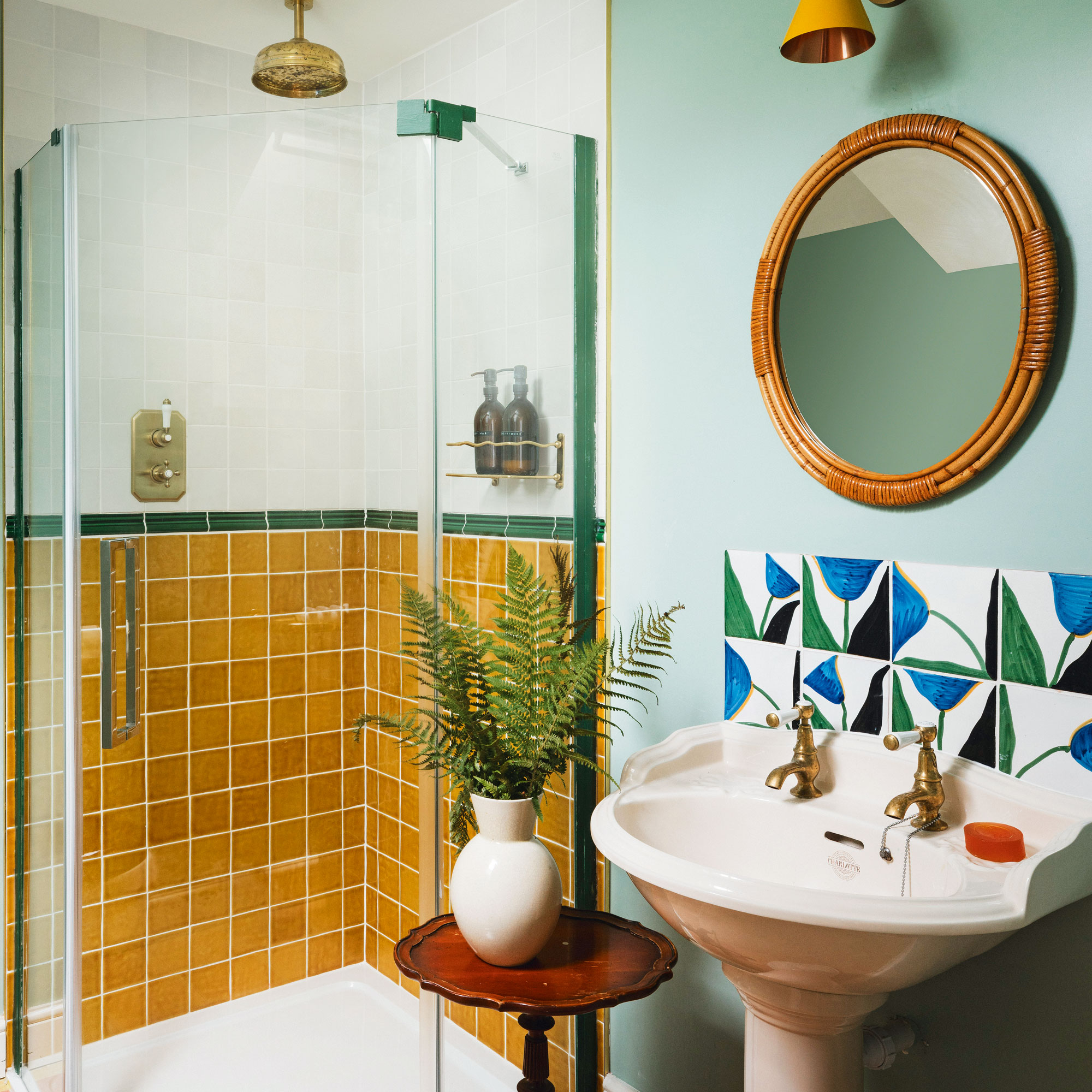 Blue bathroom with yellow tiled shower and tulip tiles behind a pink sink