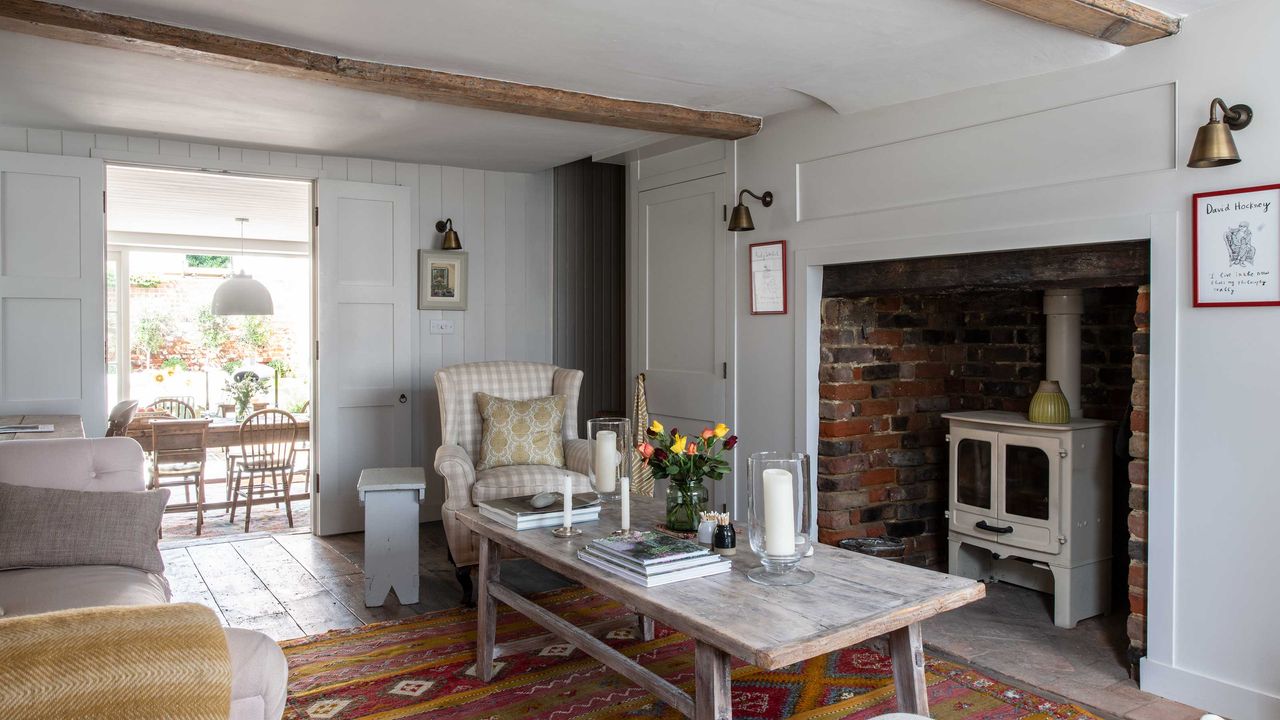 sitting room with a wood burning stove, ceiling beams, wall panelling in neutral colours