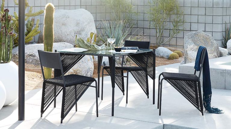 A contemporary black outdoor dining set on a patio with concrete paving