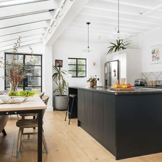 white kitchen with glass roof extension and black kitchen island