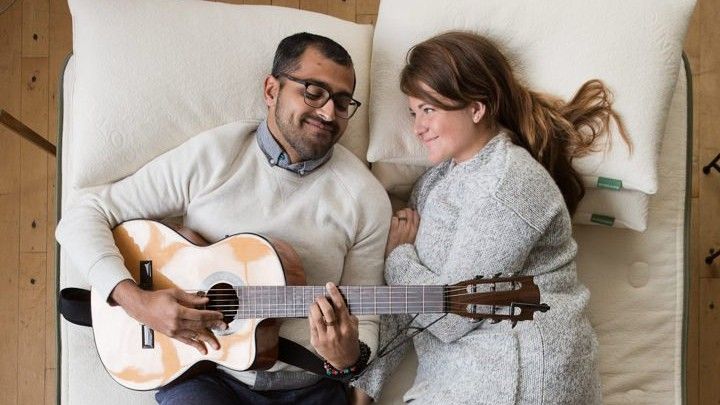 Couple lying on mattress with guitar