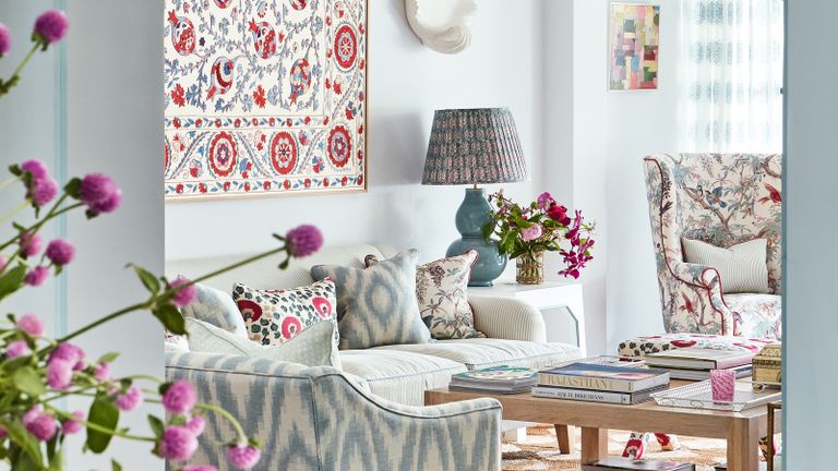 living room with white walls, pale blue arch, patterned armchairs and cushions and suzani on the wall