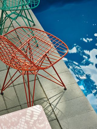 Eames wire chairs by Herman Miller and Hay in red and green, photographed by a pool