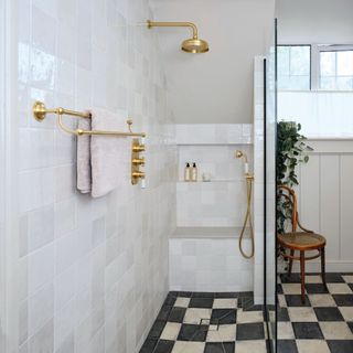 wet room with brass showerhead, black and white bathroom floor tiles and chair