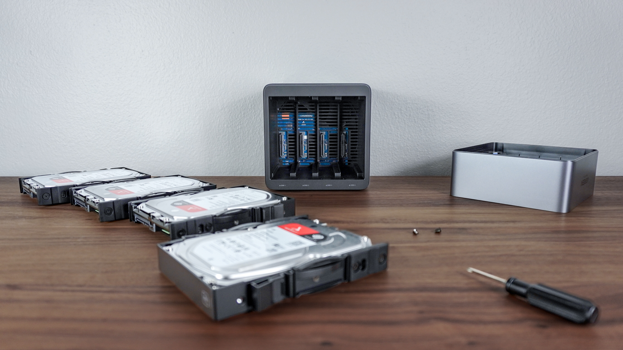 Installing four hard drives in the Ugreen NASync DH4300 Plus with all of them and the various parts needed to do so laid out on a desk