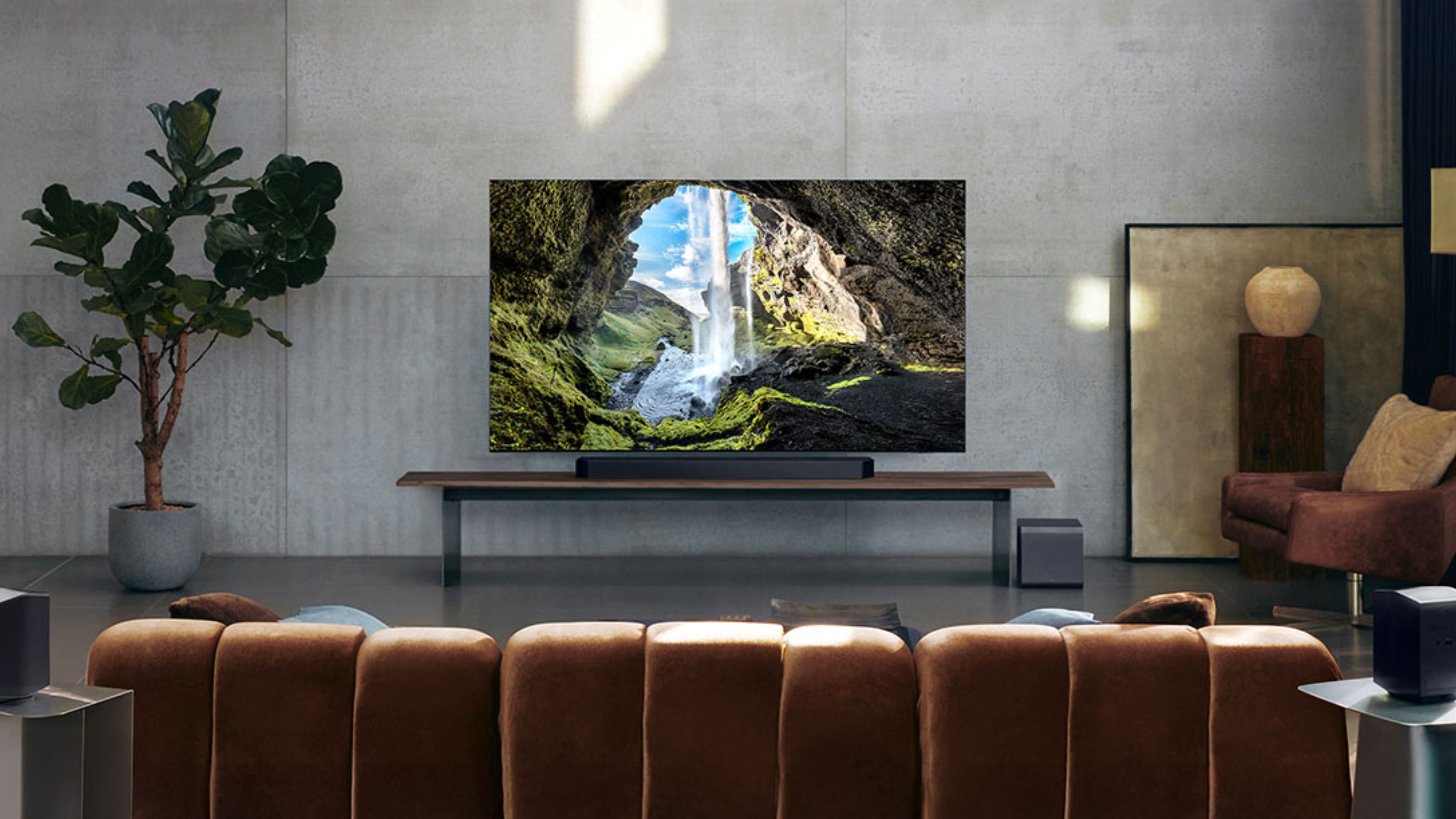a tv in a modern living room with a soundbar underneath against gray concrete slab walls