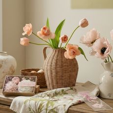 An assortment of Magnolia vases, soaps, faux flowers and tea towels on a table.
