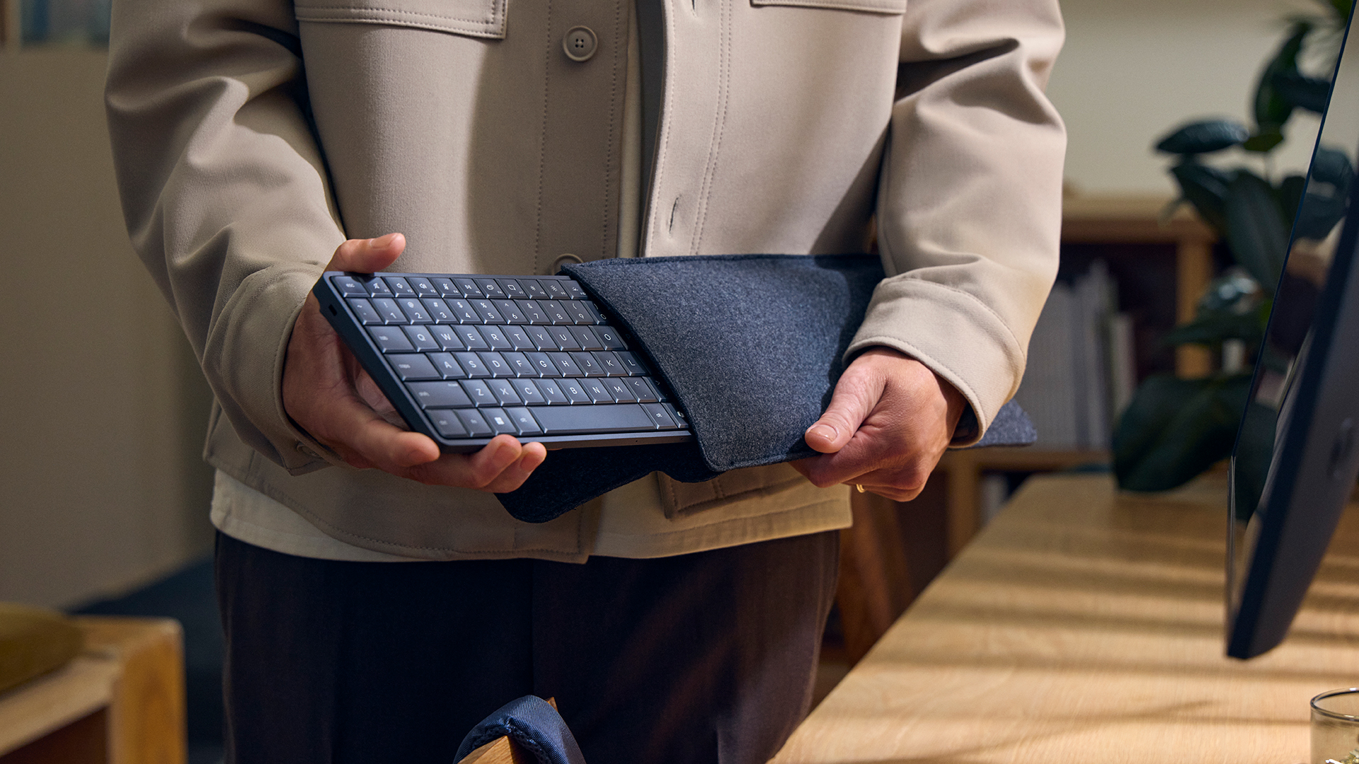 The HP EliteBoard G1a Next Gen AI PC, being held by someone inside a modern office.