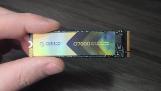 A hand holding an Orico O7000 SSD