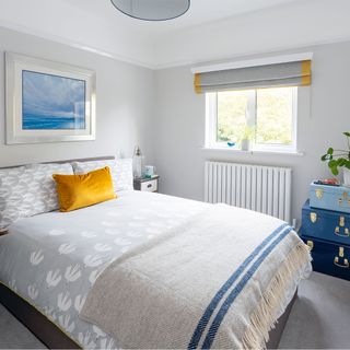 grey guest bedroom with grey bedding and yellow cushion