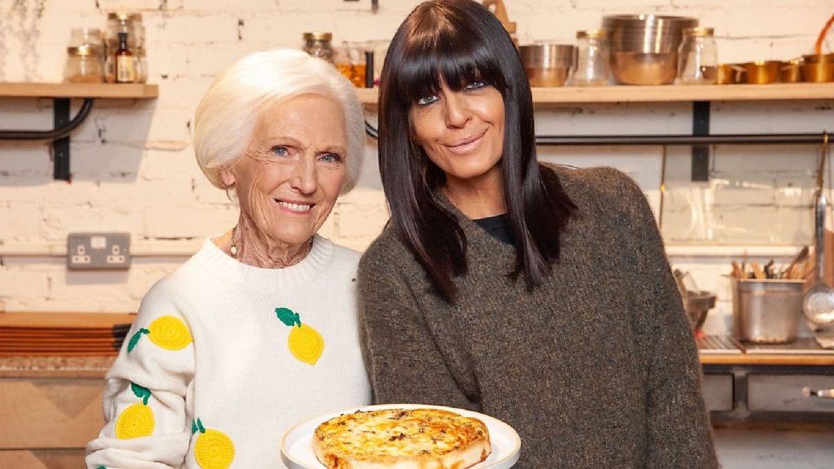 Mary Berry wearing a white jumper with prints of lemons on, holding a quick quiche and standing beside celebrity friend Claudia Winkleman in the kitchen for &quot;Mary&#039;s Foolproof Dinners&quot;.