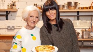 Mary Berry wearing a white jumper with prints of lemons on, holding a quick quiche and standing beside celebrity friend Claudia Winkleman in the kitchen for "Mary's Foolproof Dinners".