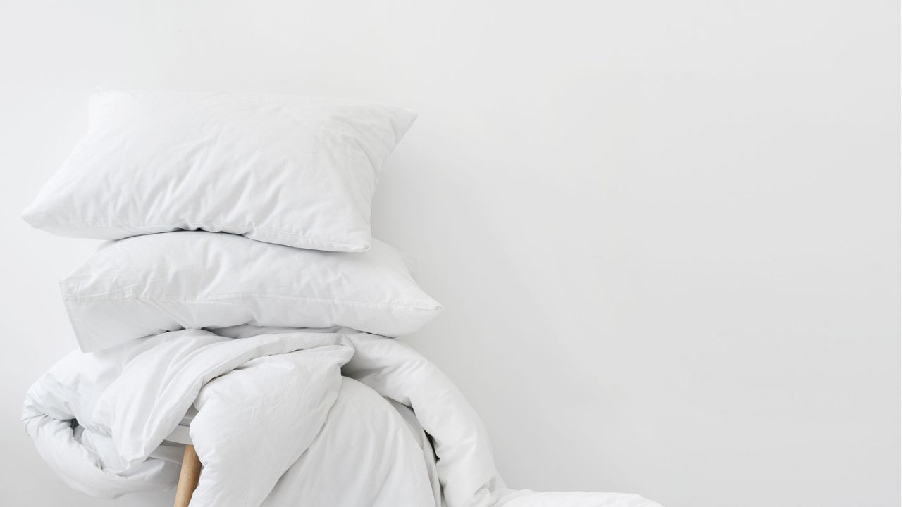 How to wash bed sheets: White bedding on bed folded up after laundry 