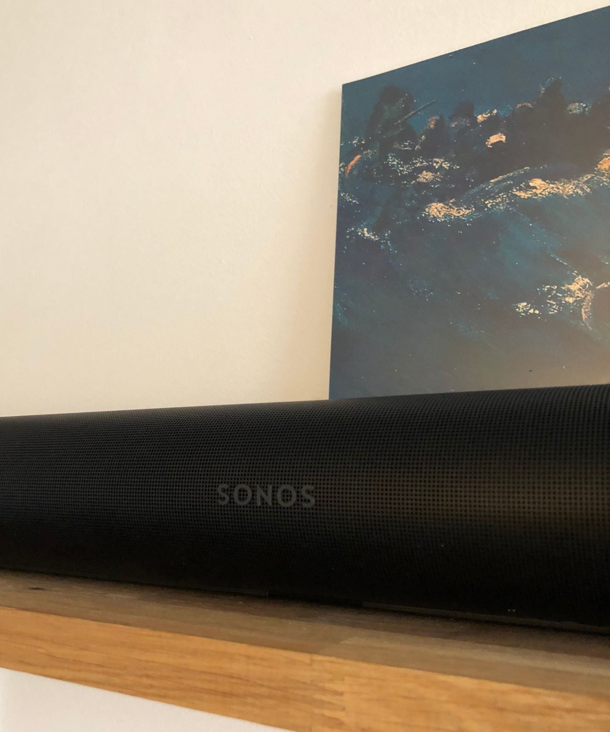 Sonos Arc Ultra soundbar on wooden shelf in front of vinyl sleeve of The Avalanches&#039; Since I Left You and white wall.