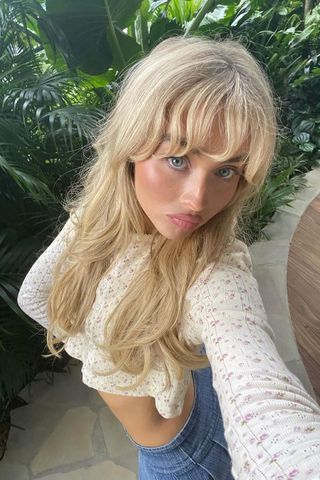 Sabrina Carpenter with blonde layered hair taking a selfie.