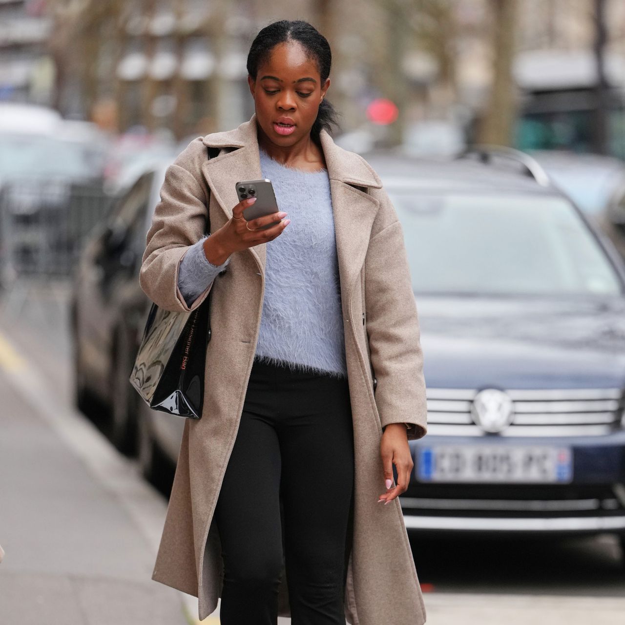 a woman wears a sweater and a trench coat