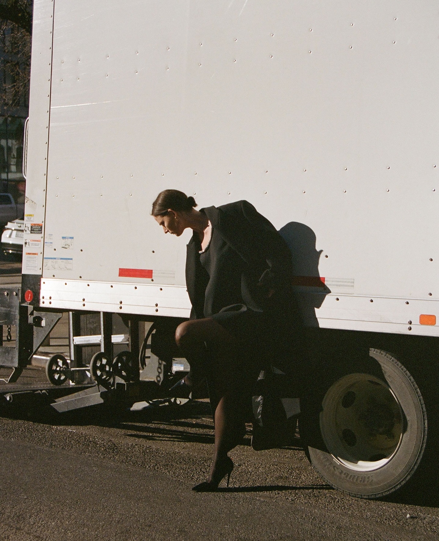 Rohe campaign shot featuring a model wearing a black dress, black blazer and heels.