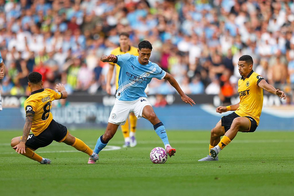 Tijjani Reijnders of Manchester City runs past Joao Gomes and Andre of Wolverhampton Wanderers during the Premier League match between Wolverhampton Wanderers and Manchester City at Molineux on August 16, 2025 in Wolverhampton, England.