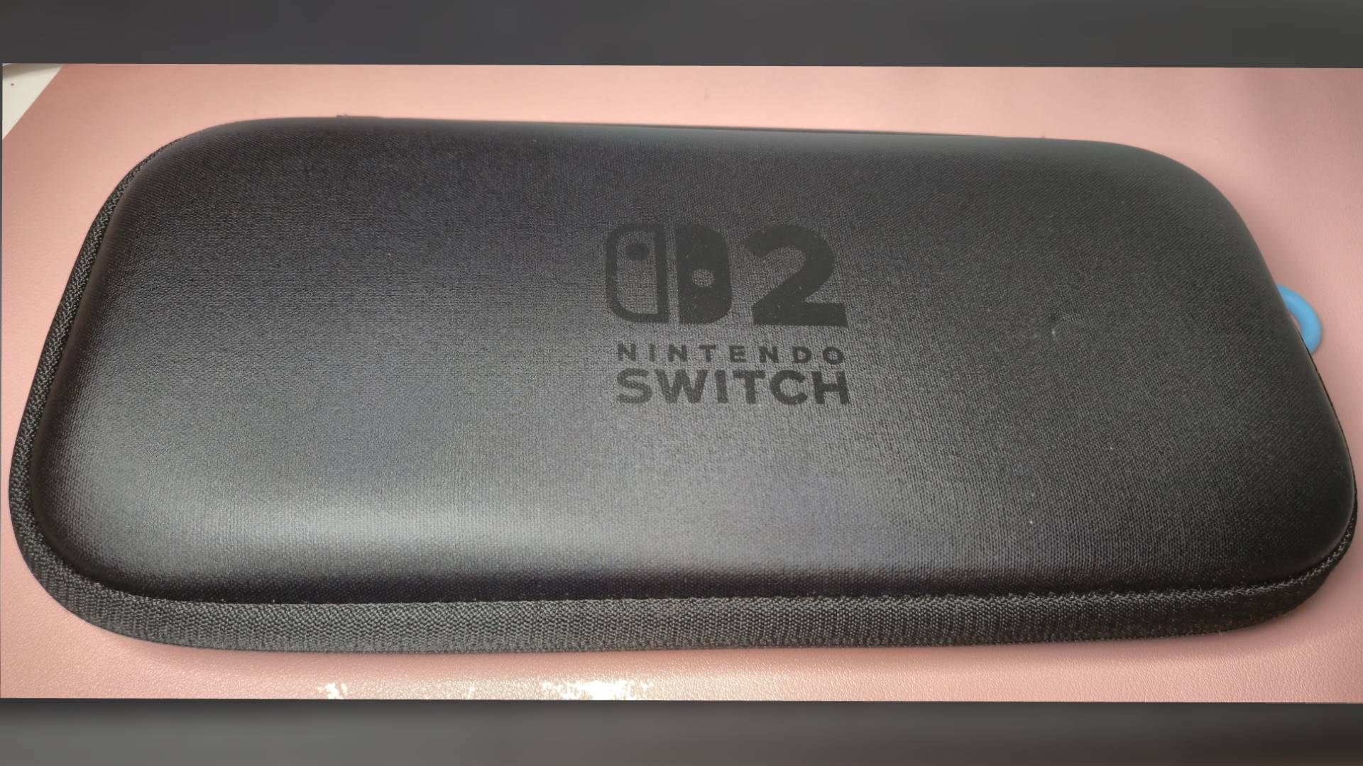 Photo of the official Switch 2 carrying case sitting on a pink gaming desk mat.