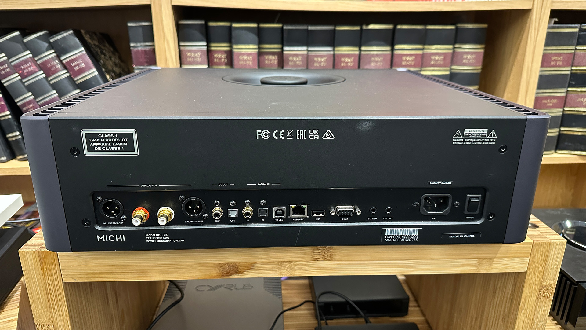 Rotel Michi Q5 CD player on wooden hi-fi rack in front of bookcase showing rear connection