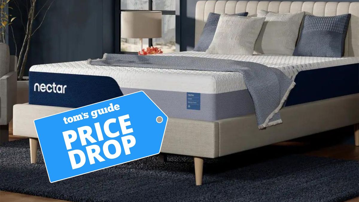 The Nectar Classic Memory Foam Mattress placed on a light grey fabric bedroom with a blue price drop sales label overlaid on the bottom of the photo