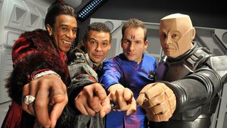 Cat, Lister, Rimmer and Kryten (L-R) pointing down the lens for Red Dwarf 9