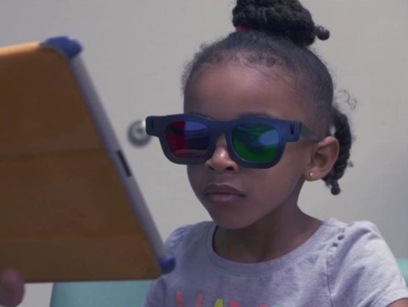 A young girl wears special glasses to play an iPad game designed to treat lazy eye.