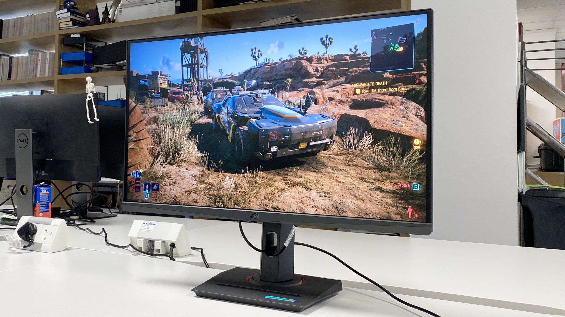 The Asus ROG Strix XG27ACS gaming monitor on a white desk.