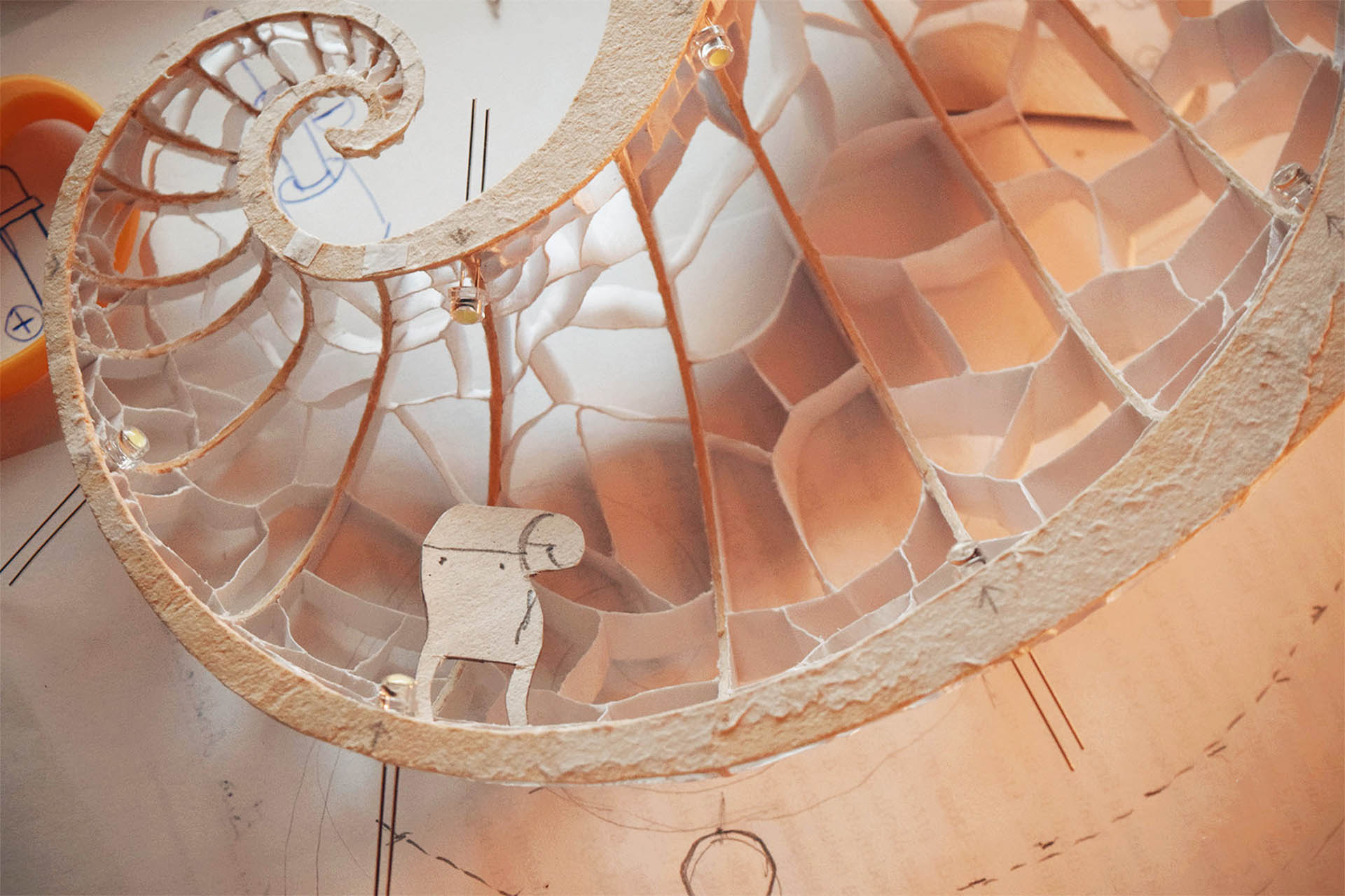 A photograph of a small, paper model that was used as an early design concept for the shell chamber.