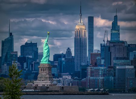 Bayonne New Jersey - April 24, 2023: View of the Statue of Liberty and the Empire State Building with the late afternoon light shining down.