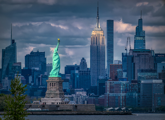 Bayonne New Jersey - April 24, 2023: View of the Statue of Liberty and the Empire State Building with the late afternoon light shining down.