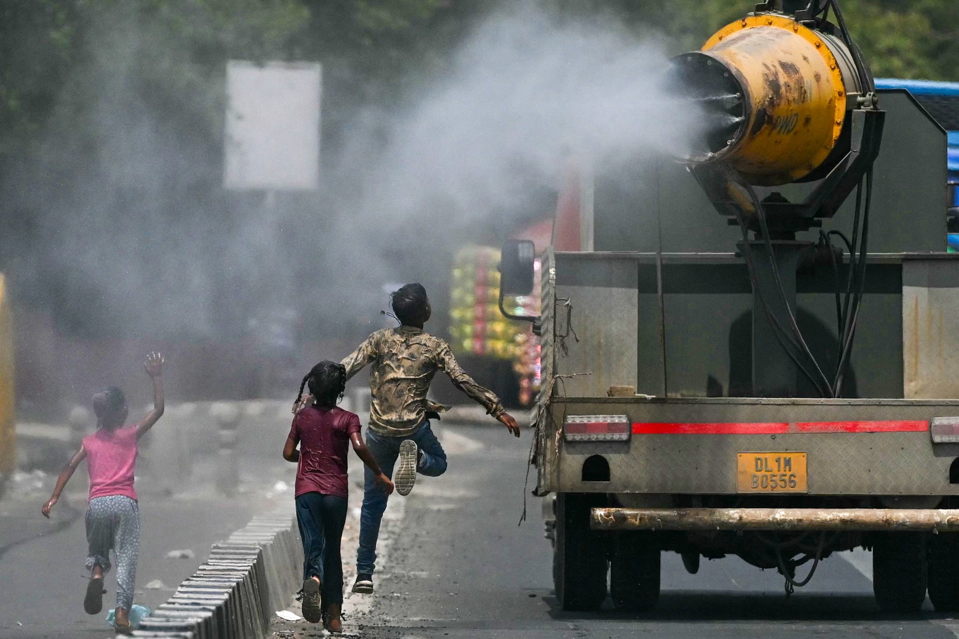 children run after truck spraying mist