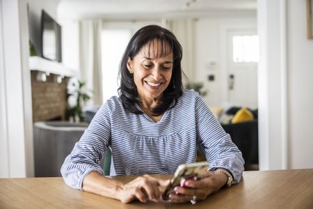 Senior woman using smartphone in dining room