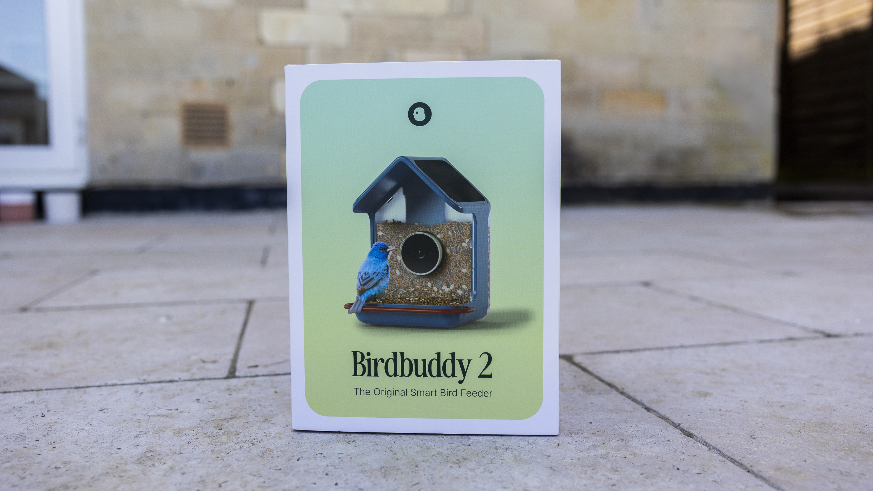 The Bird Buddy 2 box on a garden patio